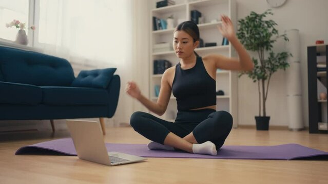 Young Asian woman doing fitness at home, watching online tutorial, motivation
