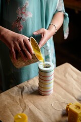 a woman makes candles with her own hands. pours wax inside the workpiece