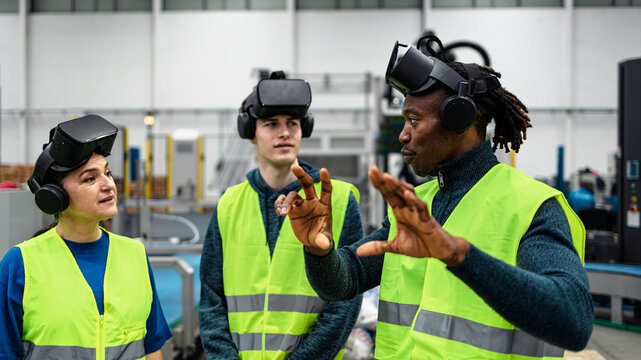 Team of multiracial engineers having a simulation experience with futuristic virtual reality glasses inside robotic factory - Tech industry and metaverse concept - Powered by Adobe