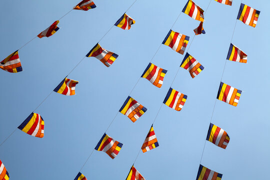 Many colorful Buddhism flags flown in the sky in a pagoda in Vietnam. Official version of a striped Buddhist flag seen in an Asian temple