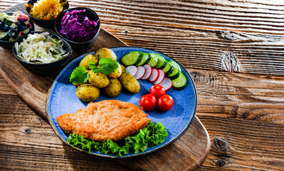 Pork cutlet coated with breadcrumbs with potatoes and salads