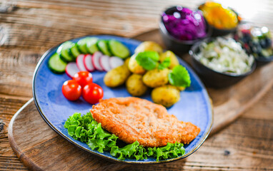 Pork cutlet coated with breadcrumbs with potatoes and salads