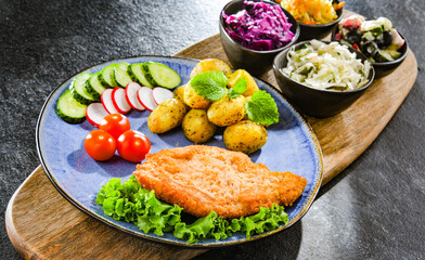 Pork cutlet coated with breadcrumbs with potatoes and salads