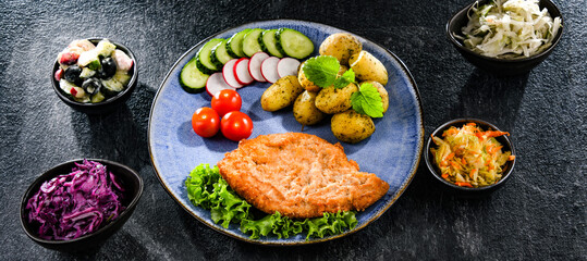 Pork cutlet coated with breadcrumbs with potatoes and salads