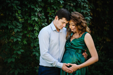 Pregnant woman and husband hugging on the tummy together in nature outdoor in vintage color tone.