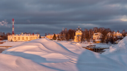 Snow drifts on cityscape background at sunset light.