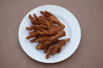 White plate of crispy fried chicken feet. Top veiw. Concept, weird, exotic food. delicious and popular street food in Thailand           