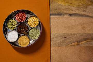 Indian spices box or Indian masala dabba on orange background and wooden background
