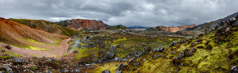 Panoramic Icelandic landscape of colorful rainbow volcanic Landmannalaugar mountains, at Laugavegur hiking trail with dramatic sky, colorful rhyolite volcano soil and lava fields in Iceland.