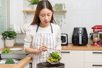 Compost from leftover food asian young housekeeper woman, female hand holding salad bowl use fork scraping waste, rotten vegetable throwing away into garbage, trash or bin. Environmentally responsible