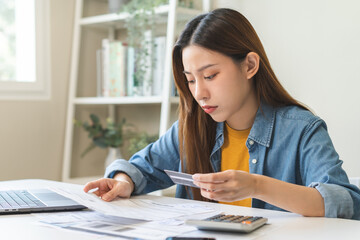 Financial owe, hand of asian woman sitting, holding credit card, stressed  by calculate expense from invoice or bill, no money to pay, mortgage or loan. Debt, bankruptcy or bankrupt.