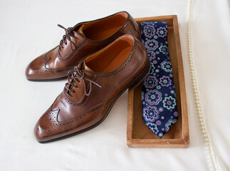 brown man leather shoes or brown man business shoes with a necktie in a wooden box on a off white scarf with pearls