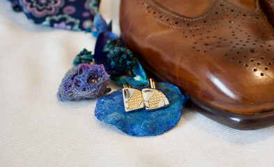 silver golden cufflinks next to brown man leather shoes and necktie