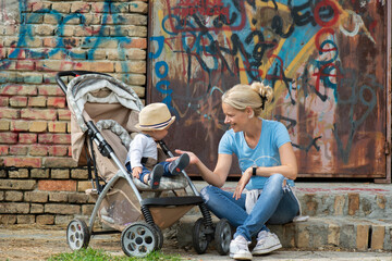 Mom is sitting on the stairs with her baby in a stroller