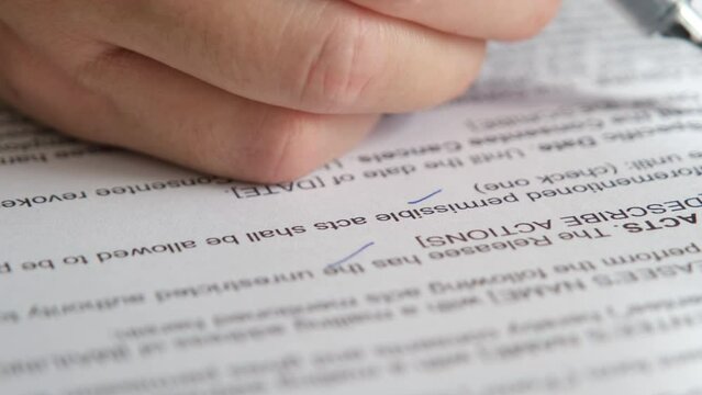 Man's hand is using a pen to check the validity of a contract or consent form.	