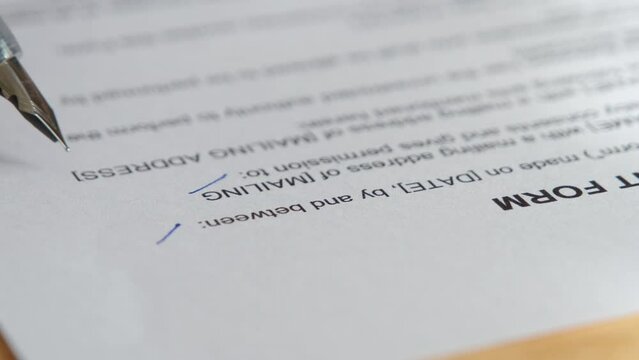 Man's hand is using a pen to check the validity of a contract or consent form.	