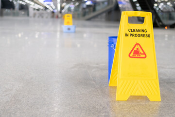 yellow plastic cone with sign showing warning of wet floor in restaurant in department store