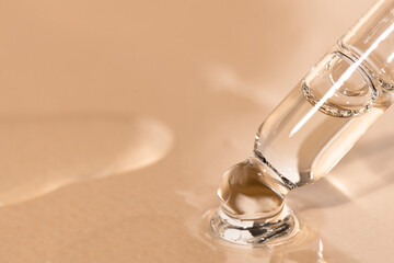 Glass dropper with cosmetic face serum close-up on a beige background. Moisturizer for make-up and skin.