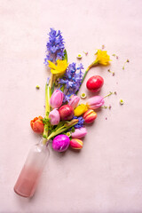Colorful spring flowers with easter eggs on tender pink background. Vetical top view flat lay for easter greetings.