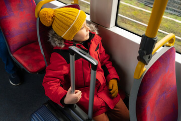 a boy with suitcase on bus or tram or train goes on trip..