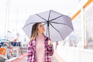 Young pretty Romanian woman holding an umbrella at outdoors with happy expression © luismolinero