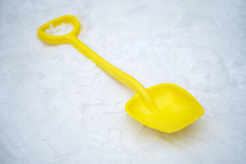 Children's toy shovel lies on the snow in the winter park
