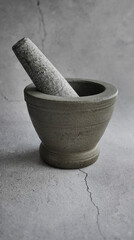 A side view of Thai granite stone mortar, grey color tone, with cracked cement floor background, same color, monochrome, kitchenware