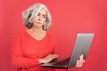 Worried mature woman standing and using a laptop