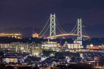 Lit Suspension Bridge Over Residential Apartments at Night