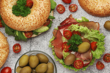 Sesame bagels with tomatoes, ham and olives