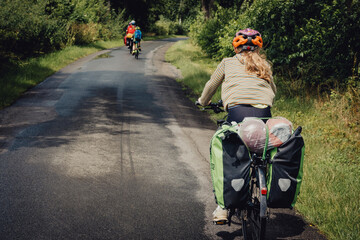 Rückansicht einer Familie während einer sommerlichen Fahrradtour durch ein Waldstück in den...