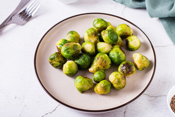 Homemade roasted Brussels sprouts on a plate and sauce in a bowl on the table.