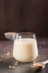 Soy milk in a glass and soybeans in a bowl on the table. Lactose free drink. Vertical view