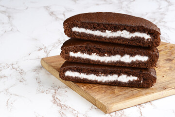 closeup of a stack of chocolate cream cake slices on cutting board