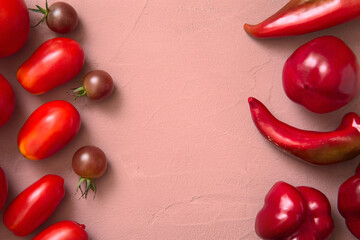 Fresh tomatoes and red peppers lying on a table, Pink background. View from above
