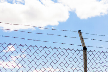 Metal fence with rusty and dangerous barbed wire, an obstacle commonly used to preserve private property