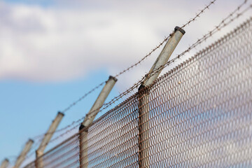 Metal fence with rusty and dangerous barbed wire, an obstacle commonly used to preserve private...