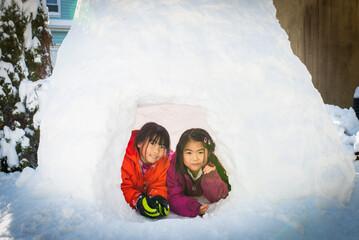Young asian girl sitting inside igloo built after snow blizzard