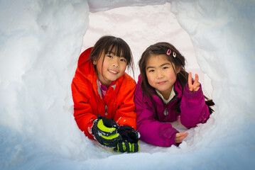 Young asian girl sitting inside igloo built after snow blizzard