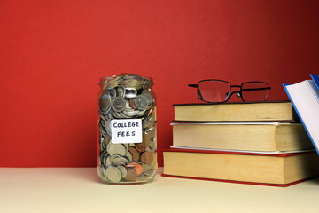 money jar labelled college fees with a stack of books and glasses
