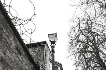 Razor wire seen on an exterior wall next to an wrought iron lamppost in the UK. An problem area...