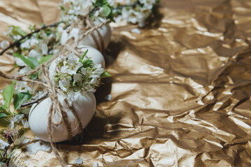 White Easter eggs with flowers on golden background, close up. Concept of Easter Sunday,  religious...