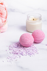 Obraz na płótnie Canvas Pink bath bombs, candle and flowers. Vertical. Bath bombs and bath salt. Berry flavor