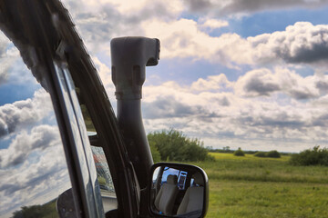 Close-up of the trunk and snorkel on the roof of a 4x4 off road car against a blue sky with clouds....