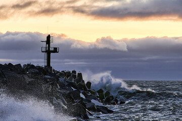 Strong waves on the stone breakwater. The beginning of the storm at the seashore