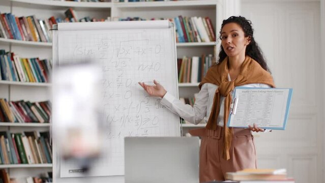 Online math lesson. Young woman tutor recording video lesson on smartphone for students, explaining mathematics