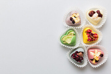 chocolate sweets in the form of a heart with fruits and nuts on a colored background. top view with space for text, holiday concept