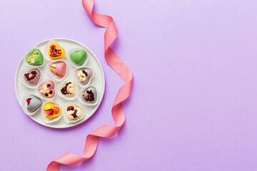 Holiday composition: sweet candy, with gift boxes with bow and chocolate hearts, photo template, background. Top View with copy space on colored background