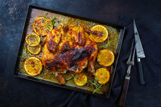 Traditional barbecue spatchcocked chicken al mattone chili with orange slices and herbs served as top view on an old rustic metal tray