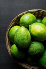 Top view of organic green limes in a basket, Top view of green limes with a dark background
